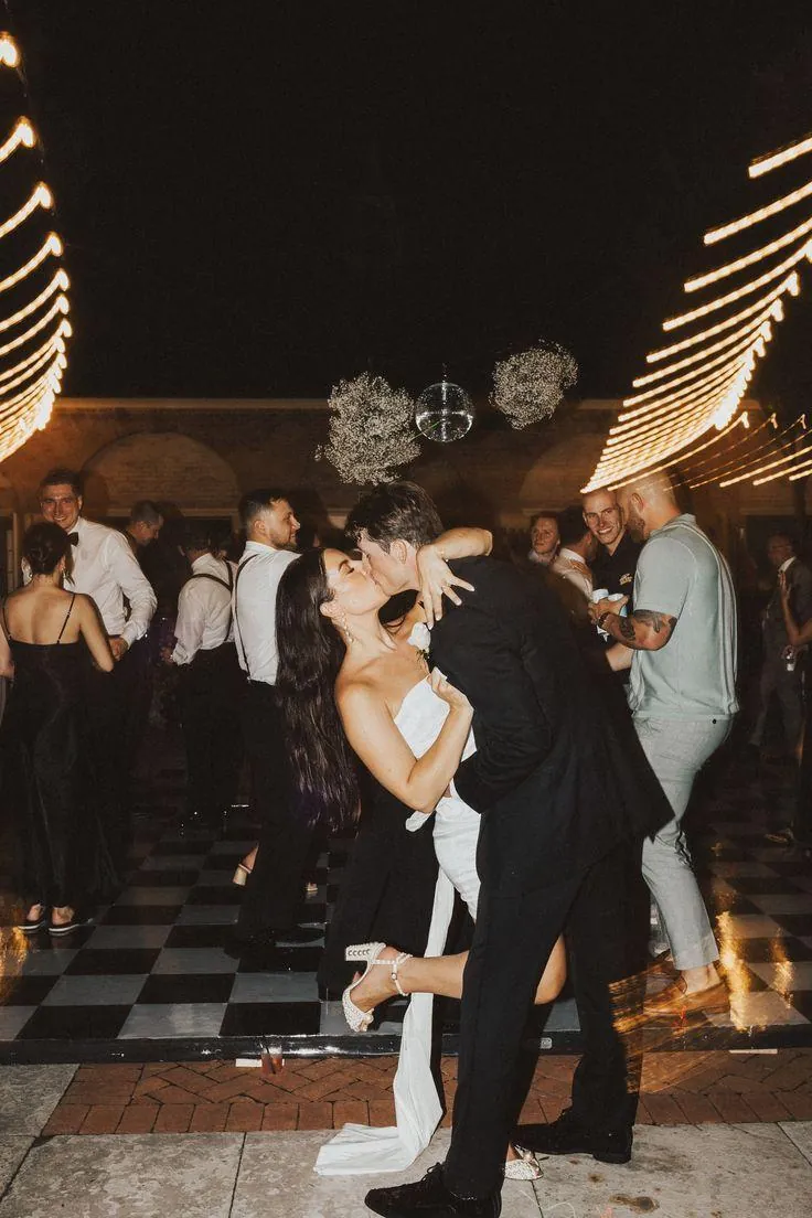 Couple kissing on the dance floor under string lights