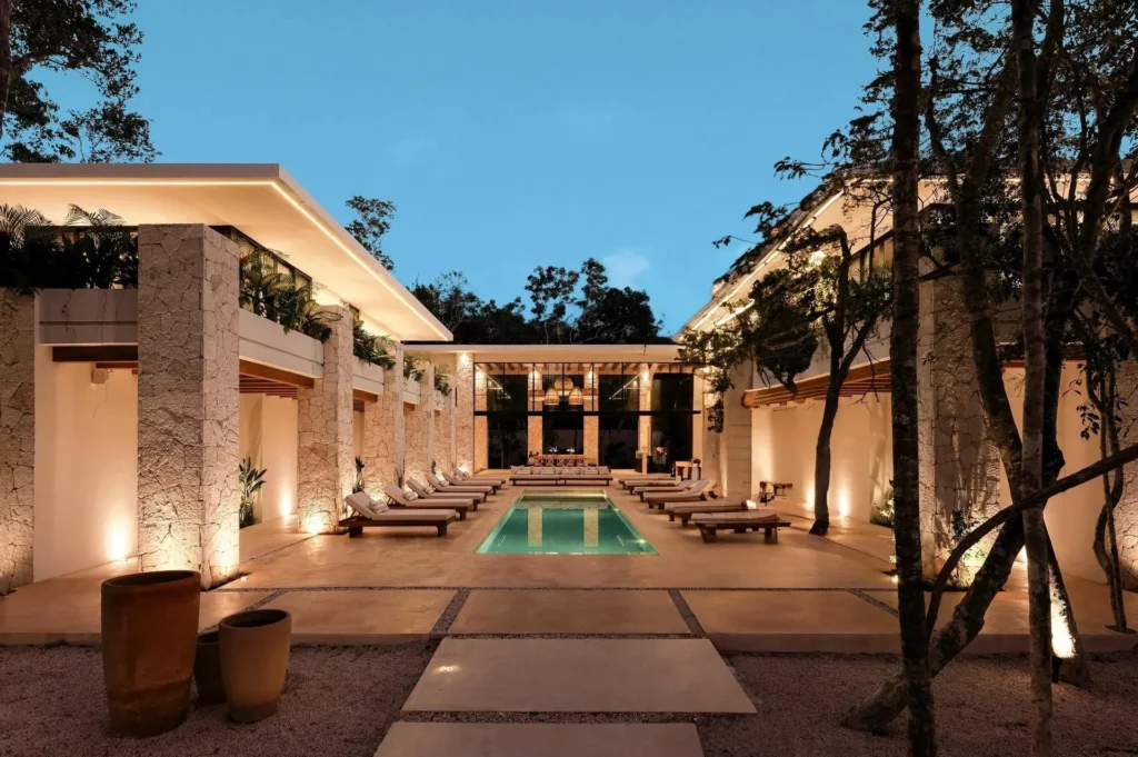 Courtyard with a lit pool and open architecture at dusk