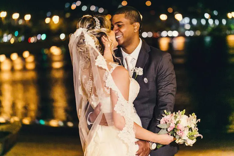 Couple embracing at night on the waterfront with city lights behind them